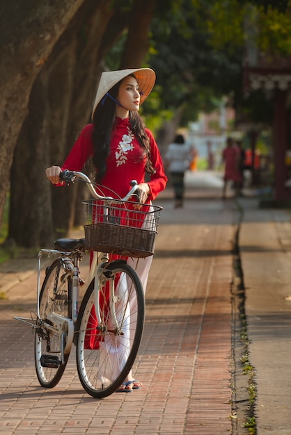 Portrait de la belle femme de fille vietnamienne en robe rouge traditionnelle avec vélo