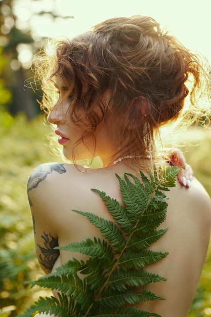 Photo portrait belle femme en forêt au coucher du soleil. la femme se repose dans la nature, un portrait d'art dans les rayons du soleil