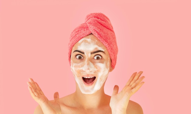 Portrait d'une belle femme heureuse appliquant une mousse nettoyante pour se laver le visage. Concept de soins de la peau