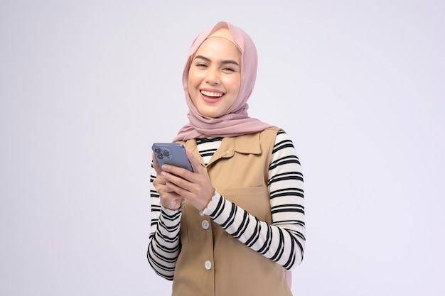 Portrait de belle femme avec hijab à l'aide de téléphone portable sur fond blanc