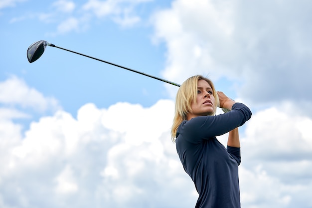 Portrait d'une belle femme jouant au golf sur un champ vert à l'extérieur. Le concept de golf, la poursuite de l'excellence, l'excellence personnelle, le sport royal.