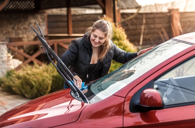 Portrait de belle femme lave le pare-brise de voiture