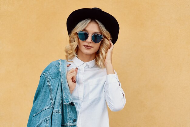 Portrait belle femme avec des lunettes de soleil et un chapeau en plein air