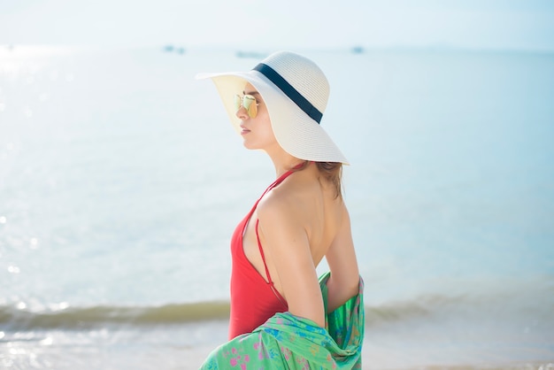 Portrait de belle femme en maillot de bain rouge relaxant sur la plage