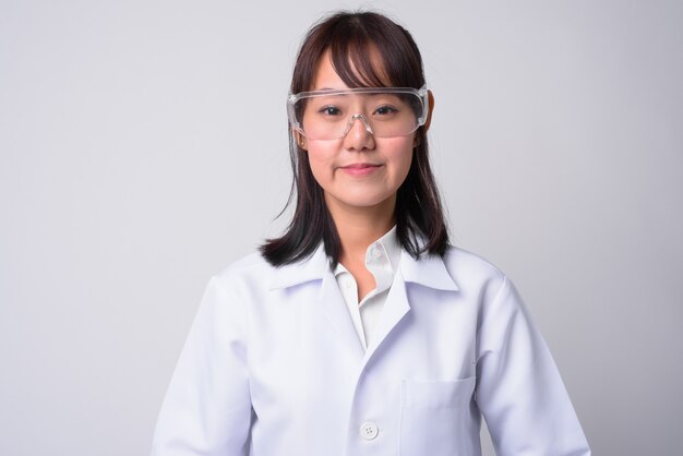 Portrait de la belle femme médecin japonaise portant des lunettes de protection sur blanc