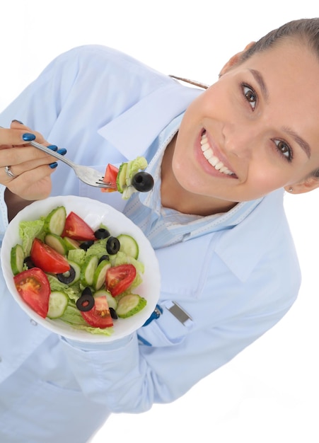 Portrait d'une belle femme médecin tenant une assiette avec des légumes frais