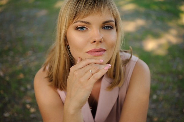 Portrait d'une belle femme méditative assise sur l'herbe verte dans le parc