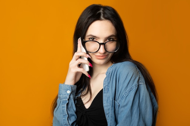 Portrait d'une belle femme mignonne avec des lunettes parlant par téléphone