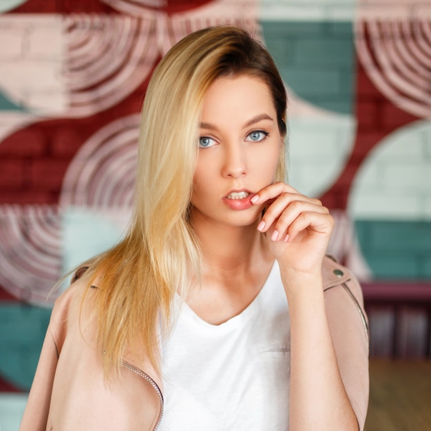 Portrait d'une belle femme à la mode dans une veste rose avec un maillot blanc dans un café