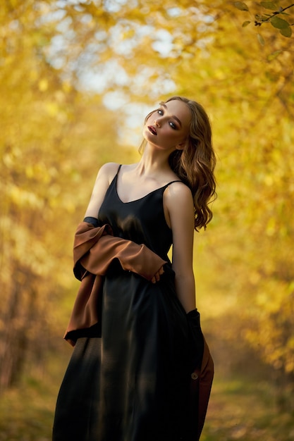 Portrait d'une belle femme de mode sur fond d'arbres d'automne jaune