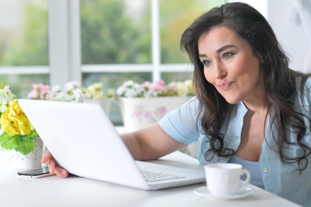 Portrait d'une belle femme mûre à l'aide d'un ordinateur portable