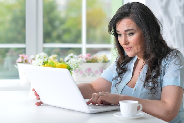 Portrait d'une belle femme mûre à l'aide d'un ordinateur portable