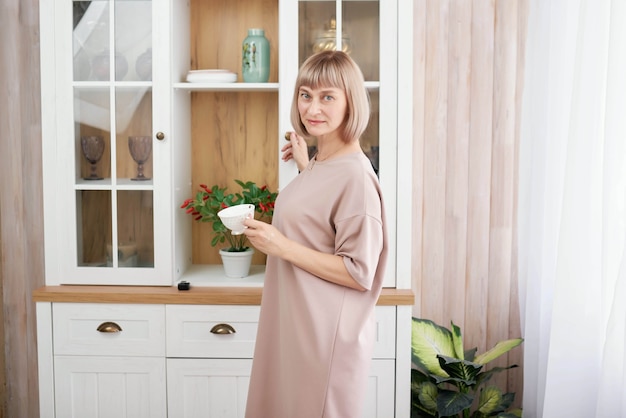 Portrait d'une belle femme mûre assise dans la cuisine moderne.