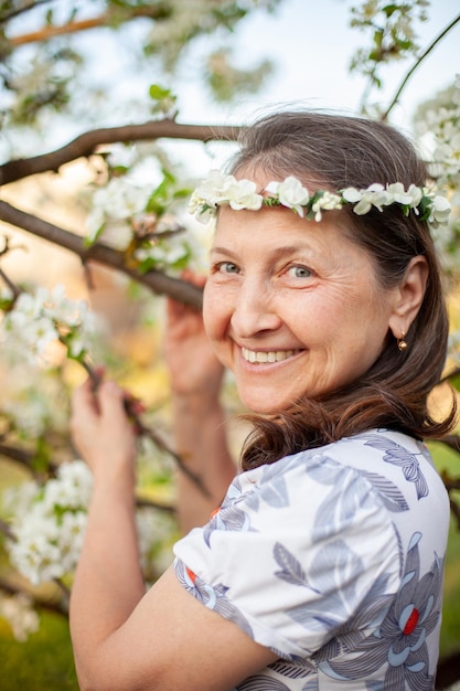 Portrait d'une belle femme mûre en robe légère sur fond de jardins fleuris au printemps