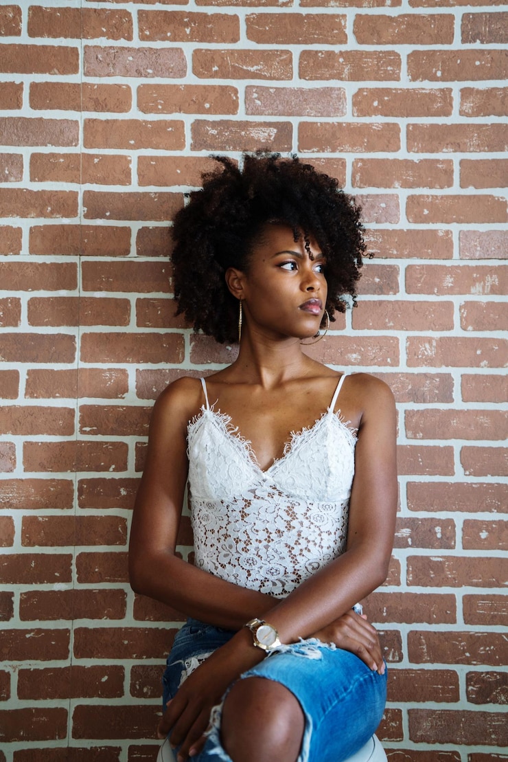 Photo portrait d'une belle femme noire avec un afro sur le fond d'un mur de briques