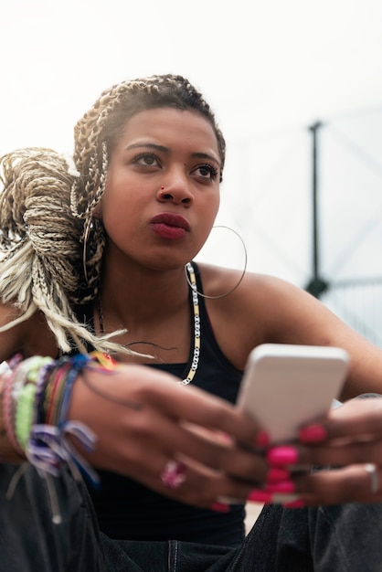 Portrait d'une belle femme noire utilisant son téléphone portable dans son quartier. Concept de bidonville.