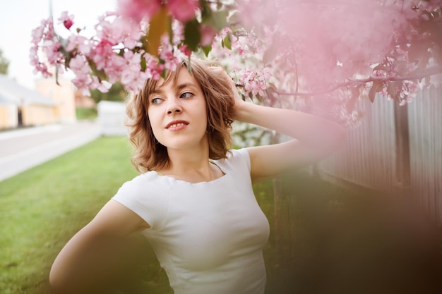 Portrait d'une belle femme parmi les fleurs bokeh roses à l'extérieur au printemps mise au point sélective