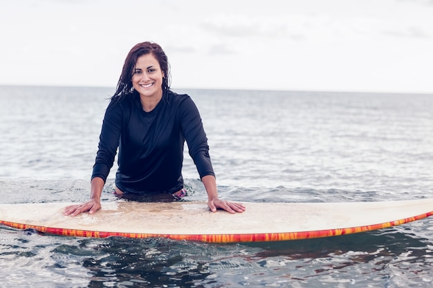 Portrait d&#39;une belle femme avec planche de surf dans l&#39;eau