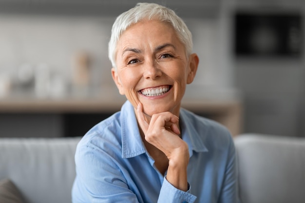 Portrait d'une belle femme plus âgée souriant à la caméra touchant le menton