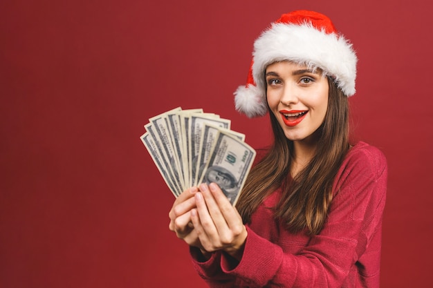 Portrait de la belle femme portant Bonnet de Noel et tenant des billets en dollars