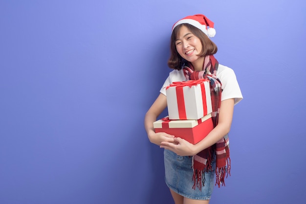 Un portrait de la belle femme portant un chapeau de père Noël rouge tenant une boîte-cadeau sur studio