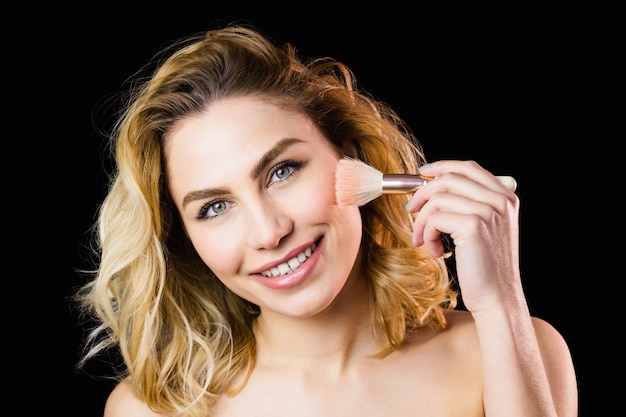 Portrait de la belle femme posant avec un pinceau de maquillage