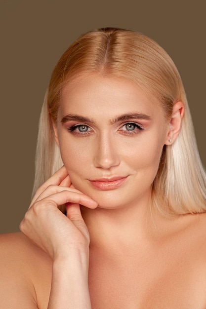 Portrait de belle femme Rajeunissement de la peau Dame blonde avec maquillage naturel souriant isolé sur marron