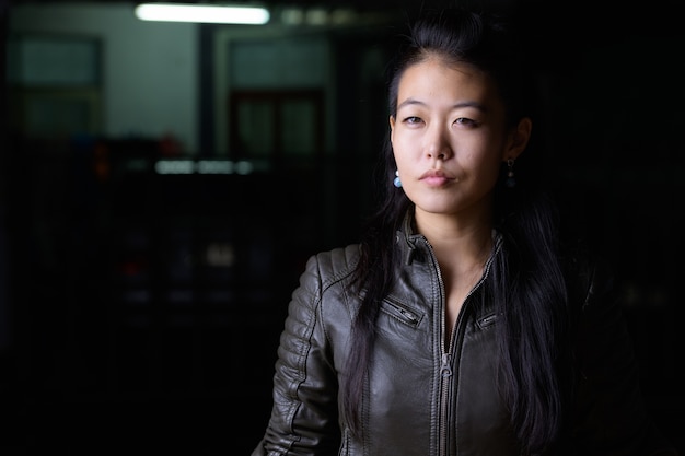 Portrait de la belle femme rebelle asiatique portant une veste en cuir dans les rues à l'extérieur la nuit