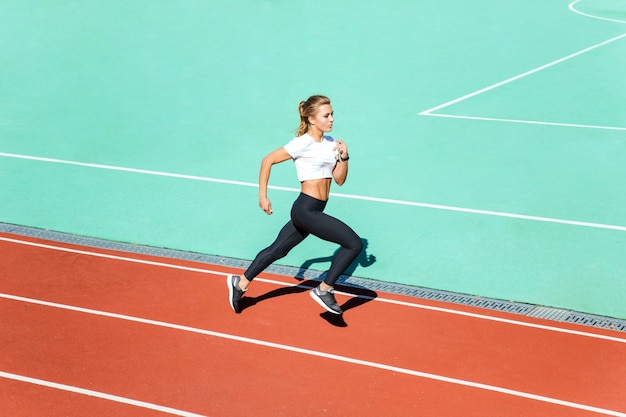 Portrait d'une belle femme de remise en forme en cours d'exécution au stade