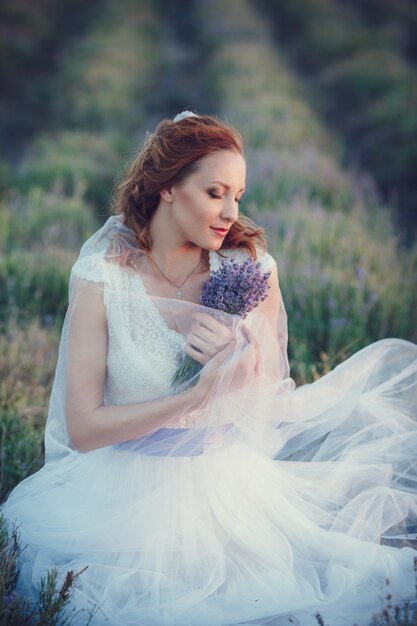 Portrait de la belle femme romantique dans le champ de fées de lavande avec bouquet