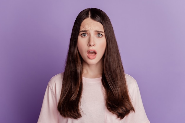 Portrait d'une belle femme sans voix bouche ouverte regarde la caméra sur le mur violet