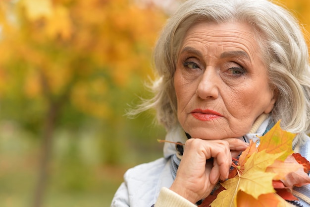 Portrait d'une belle femme senior triste sur fond d'automne flou