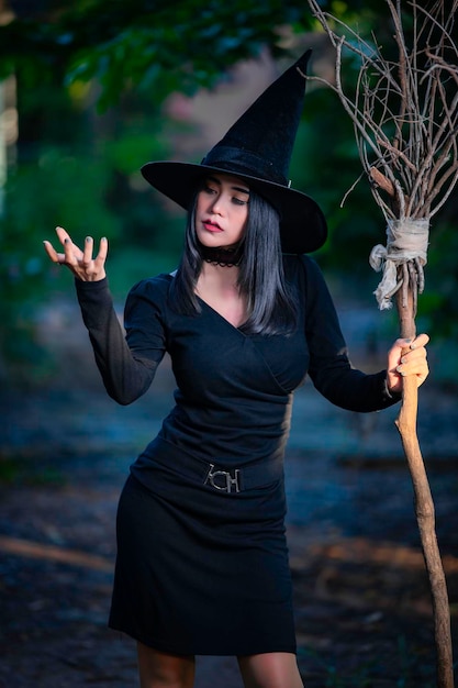 Portrait de belle femme sexy asiatique porter un costume de sorcière noire avec balaiconcept de festival Halloween