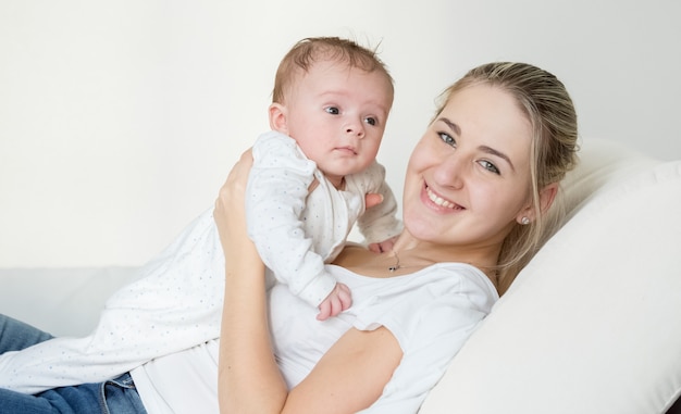 Portrait d'une belle femme souriante allongée avec son bébé mignon sur un oreiller au lit