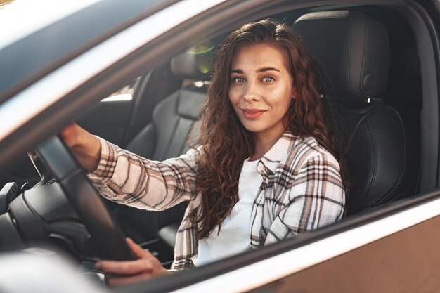 Photo portrait d'une belle femme souriante dans une voiture regardant par la fenêtre