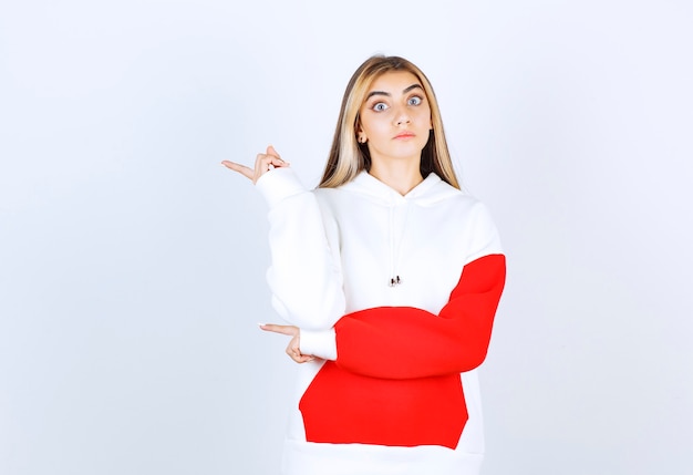 Portrait d'une belle femme en sweat à capuche chaud debout et pointant vers l'extérieur