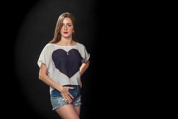 portrait de belle femme en t-shirt avec coeur sur fond noir