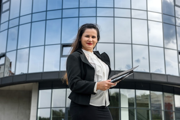 Portrait d'une belle femme avec une tablette à l'extérieur près du grand centre de bureaux