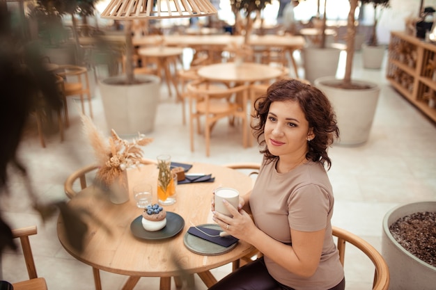 Portrait d'une belle femme avec une tasse de café dans ses mains dans un café de la ville