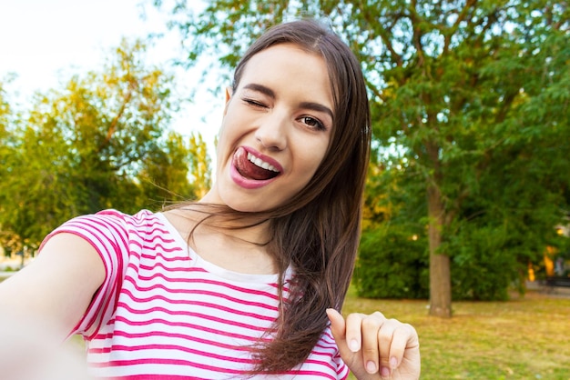 Portrait d'une belle femme tendant la langue dans le parc
