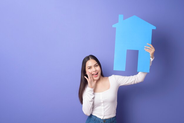 Portrait de la belle femme tient la maison bleue sur fond violet