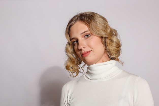 Portrait de belle femme transgenre aux cheveux blonds sur fond gris