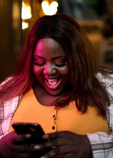 Photo portrait de belle femme utilisant un smartphone la nuit dans les lumières de la ville