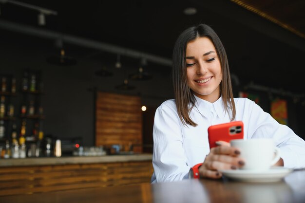 Portrait de belle fille à l'aide de son téléphone portable au café.