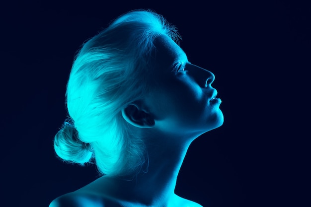 Portrait de belle fille albinos isolée sur fond de studio sombre à la lumière du néon