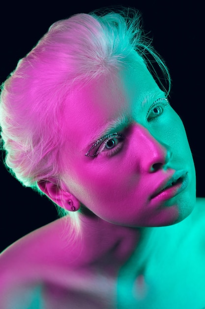 Portrait de belle fille albinos isolée sur fond de studio sombre à la lumière du néon