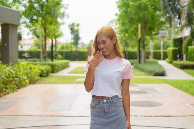 Portrait d'une belle fille asiatique aux cheveux blonds souriante et regardant vers le bas en riant