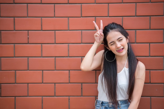 Portrait d'une belle fille asiatique chic pose pour prendre une photo sur fond de mur