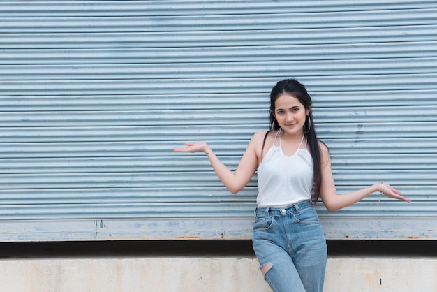 Portrait d'une belle fille asiatique chic pose pour prendre une photo sur fond de mur