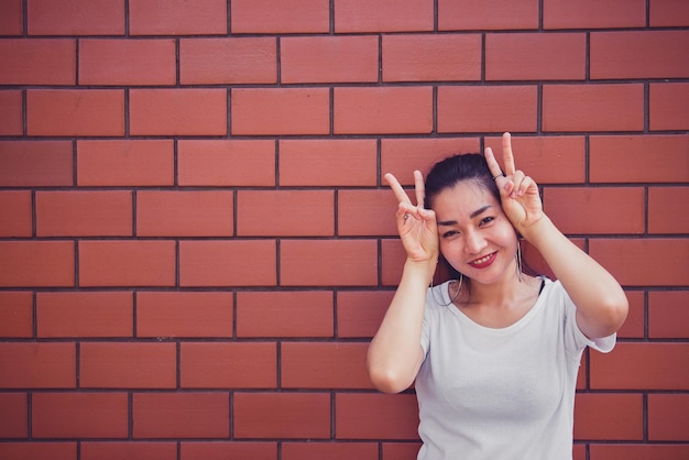 Portrait d'une belle fille asiatique chic pose pour prendre une photo sur un mur de briques